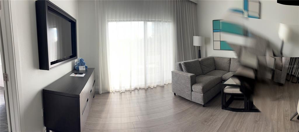 A living room features a grey sectional sofa, a dark wood dresser, and a wall-mounted television — 14501 GROVE RESORT AVENUE UNIT 3220, KISSIMMEE, FL