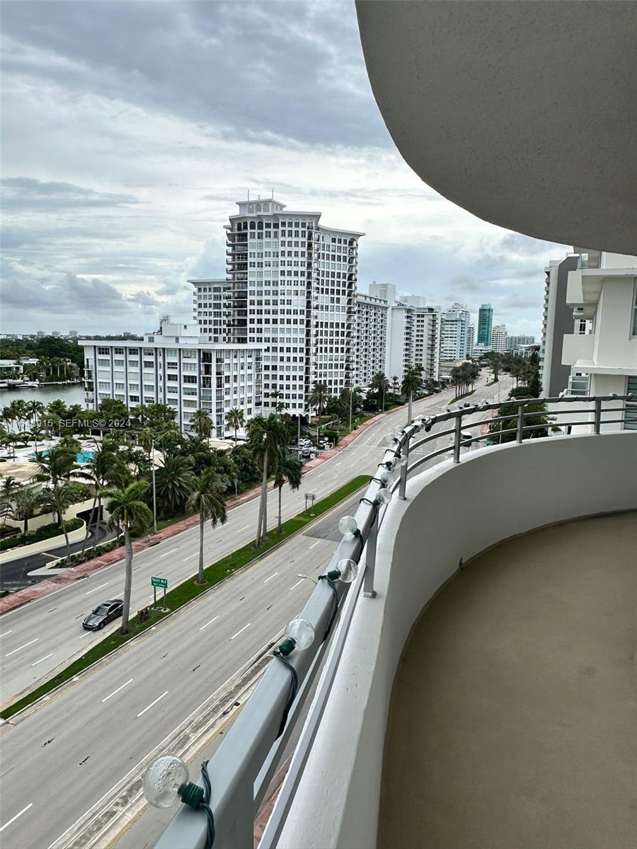 A balcony with string lights overlooks a multi-lane road and high-rise buildings — 5555 Collins Ave # 10B, Miami Beach FL 33140, MIAMI BEACH, FL