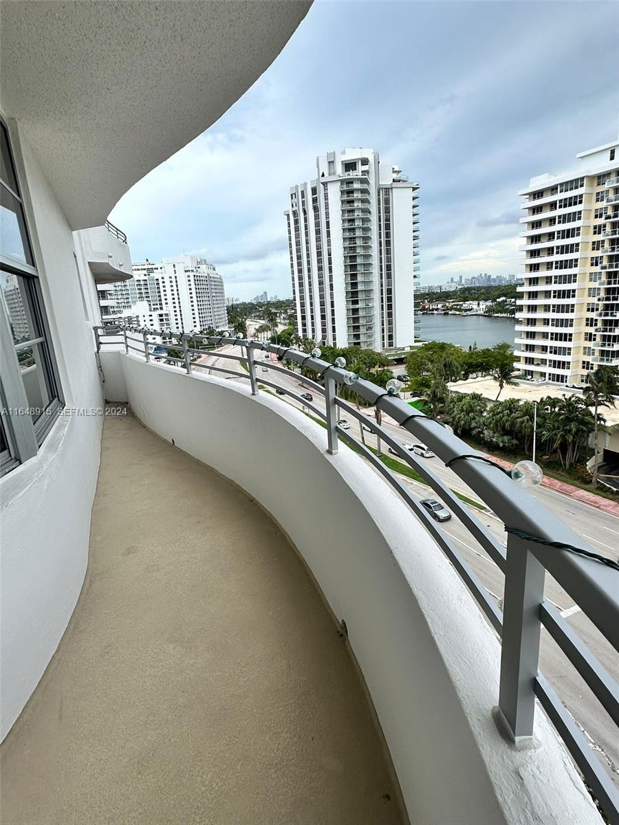 A curved balcony overlooks a coastal road, a waterway, and several high-rise apartment buildings — 5555 Collins Ave # 10B, Miami Beach FL 33140, MIAMI BEACH, FL
