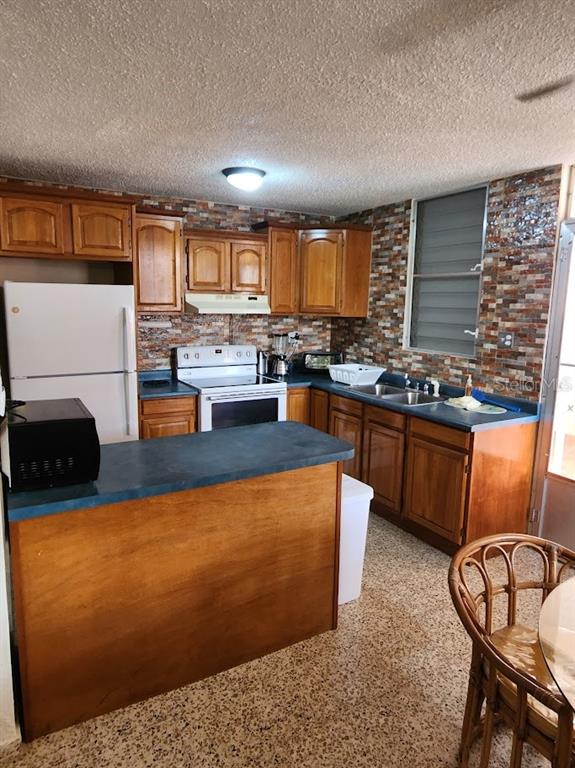 A kitchen features wood cabinets, a blue countertop, a white stove, and a stone backsplash — 4-14 bloque 4k-10 ALTURAS DE MONTE BRISAS, FAJARDO, PR