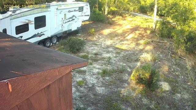 A white travel trailer is parked on a dirt lot next to a wooden structure — Tbd Sw Sands Point Ave, FL 34431, FL