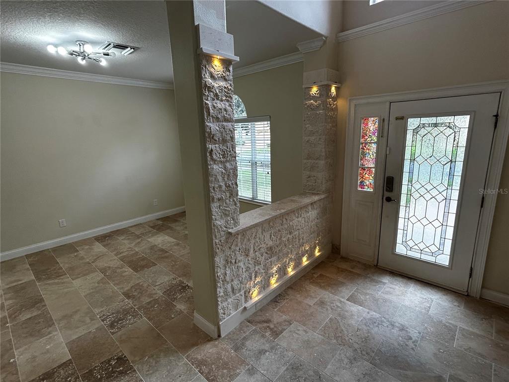 An entryway features a stone half-wall divider, tile flooring, and a decorative glass front door — 6850 DOLCE STREET, ORLANDO, FL