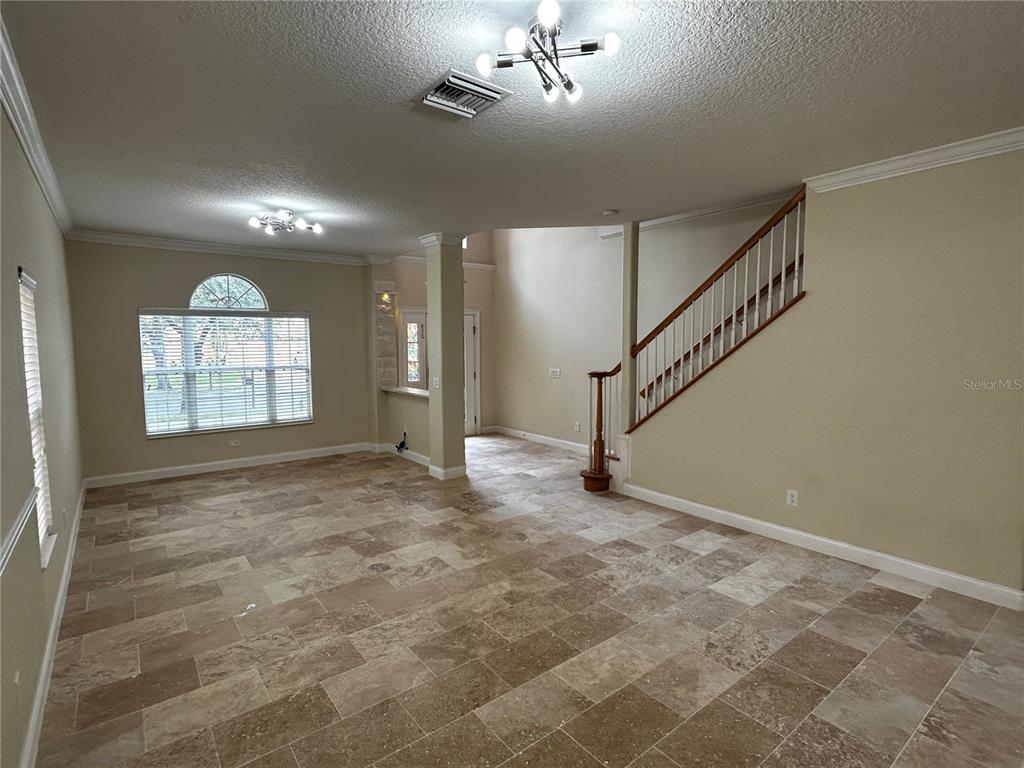 An open living area features tile flooring, a staircase with a wooden railing, and windows — 6850 DOLCE STREET, ORLANDO, FL