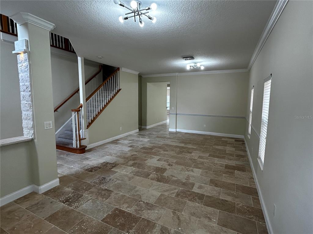 An open living area features tile flooring, a staircase with a wooden railing, and light-colored walls — 6850 DOLCE STREET, ORLANDO, FL