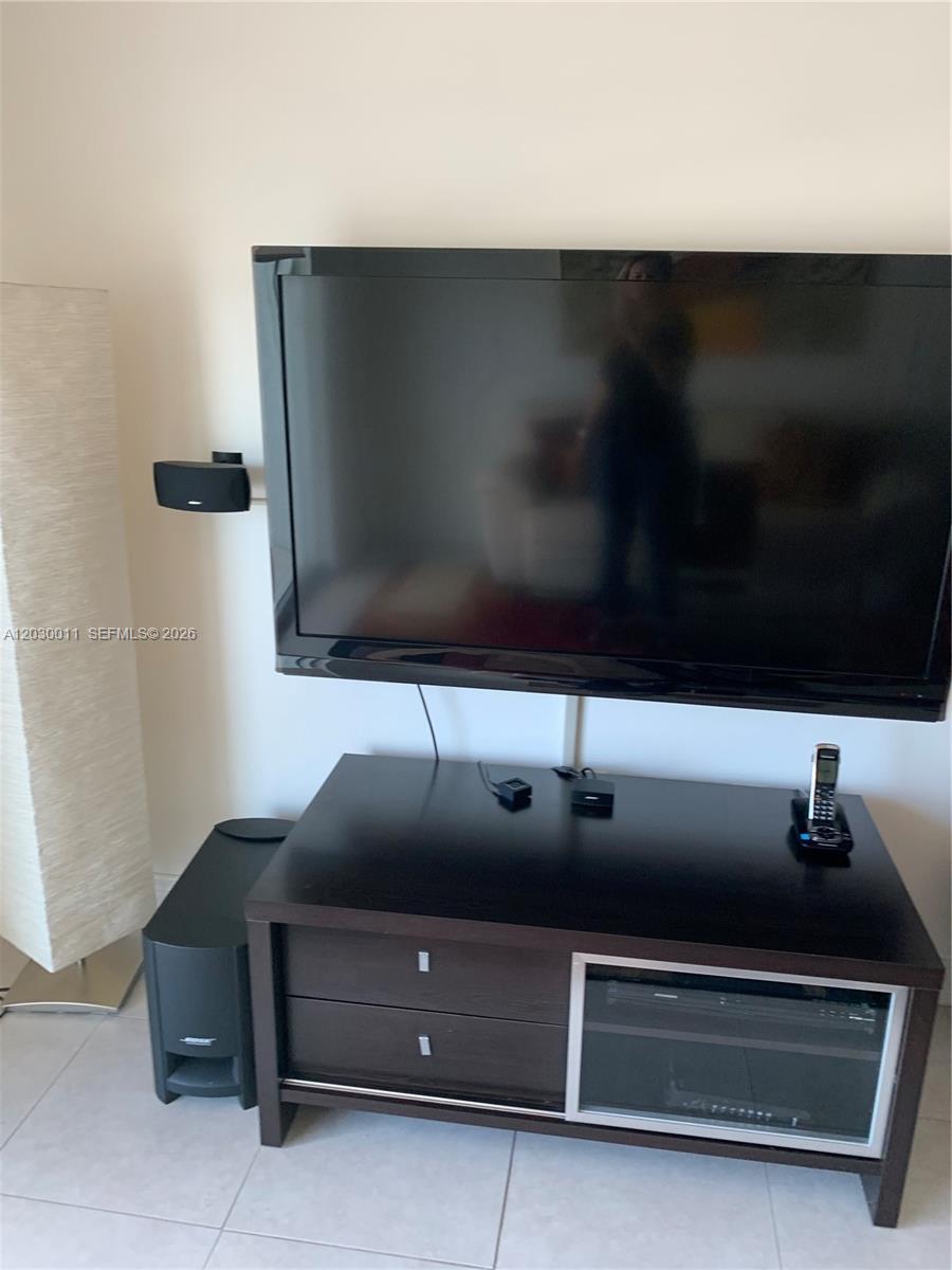 A kitchen with white cabinets, granite countertops, and stainless steel appliances overlooks a living area — 275 NE 18th # 1709, Miami FL 33132, MIAMI, FL