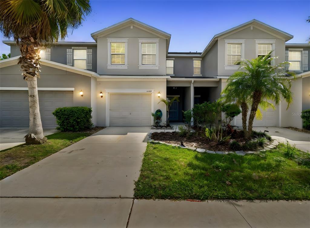 A two-story townhouse exterior features a concrete driveway, a garage, and a small front yard — 10687 LAKE MONTAUK DRIVE, RIVERVIEW, FL