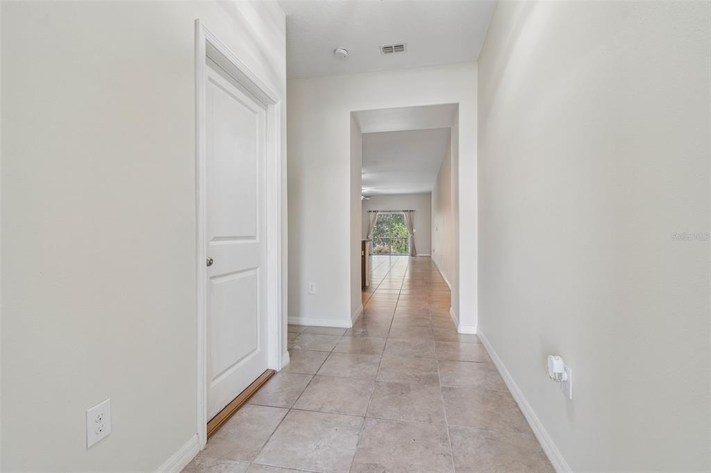 A tiled hallway leads from a white door toward an open living area with windows — 10687 LAKE MONTAUK DRIVE, RIVERVIEW, FL