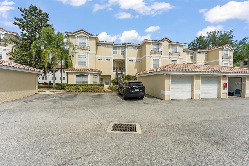 A multi-story apartment building with a parking lot and detached garages in the foreground — 674 SANDY NECK LANE UNIT 102, ALTAMONTE SPRINGS, FL
