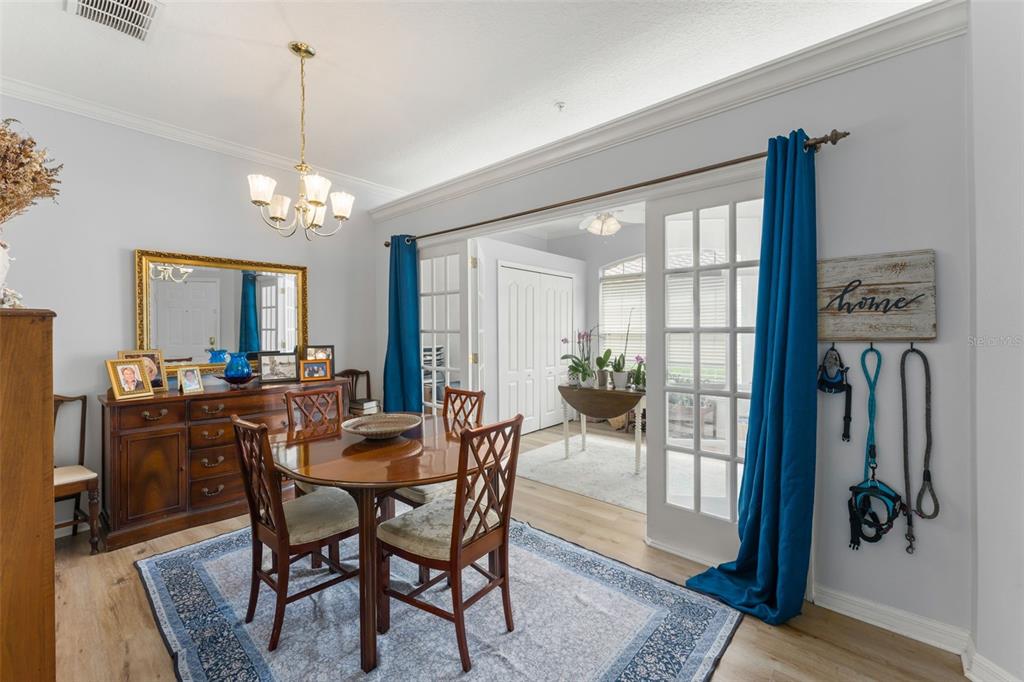 A dining room features a wooden table, chairs, a sideboard, and French doors leading outside — 674 SANDY NECK LANE UNIT 102, ALTAMONTE SPRINGS, FL