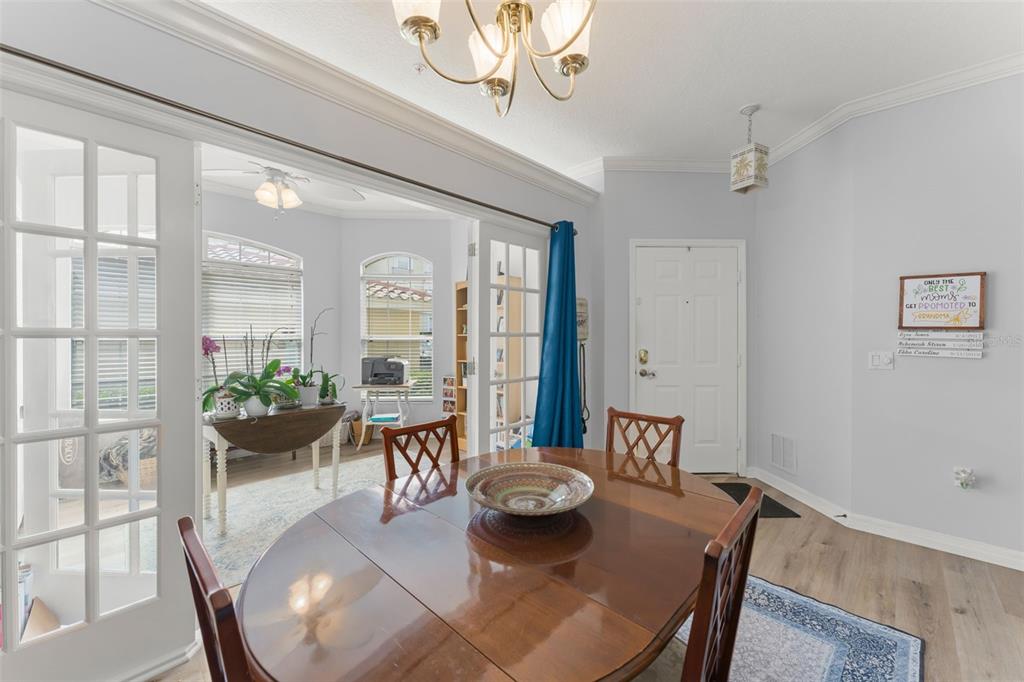 A dining room with a wooden table, chandelier, and French doors leading to a sunroom — 674 SANDY NECK LANE UNIT 102, ALTAMONTE SPRINGS, FL