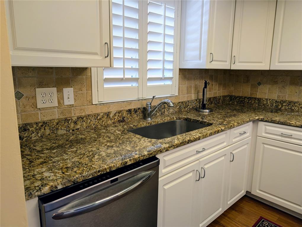 A kitchen features white cabinets, granite countertops, a stainless steel sink, and a dishwasher — 3807 LAKE BAYSHORE DRIVE UNIT H-416, BRADENTON, FL