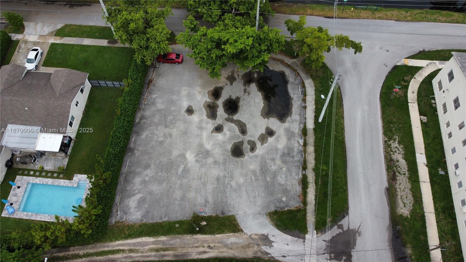 An aerial view shows a vacant, paved lot with several puddles and surrounding trees — 425 Esplanade Dr, Miami Springs FL 33166, MIAMI SPRINGS, FL