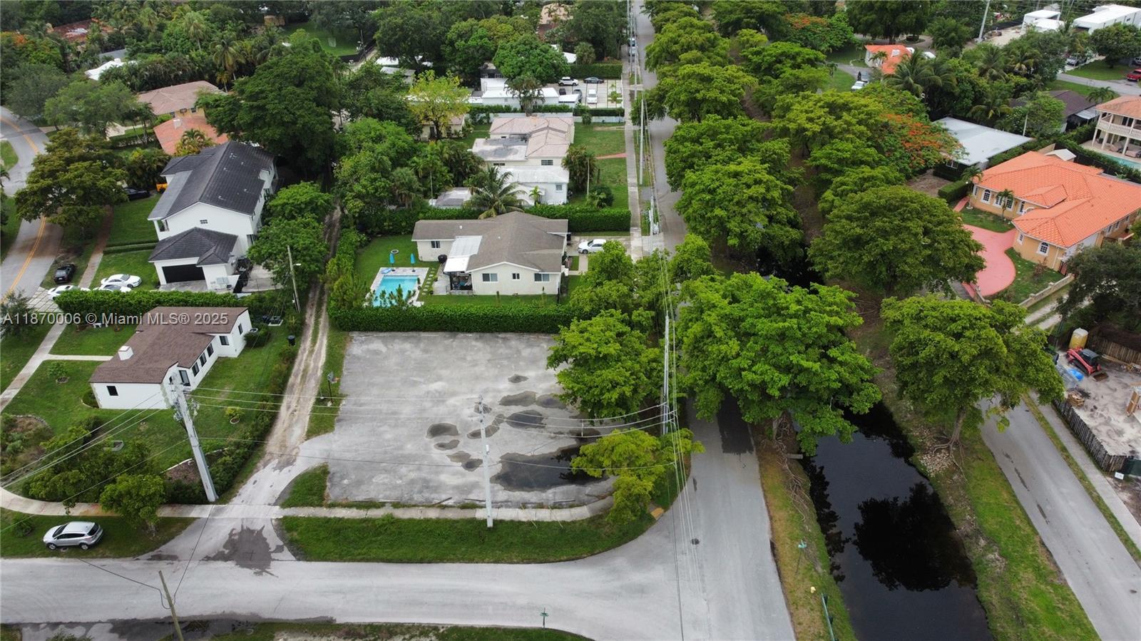 An aerial view shows a vacant paved lot next to a house with a pool — 425 Esplanade Dr, Miami Springs FL 33166, MIAMI SPRINGS, FL