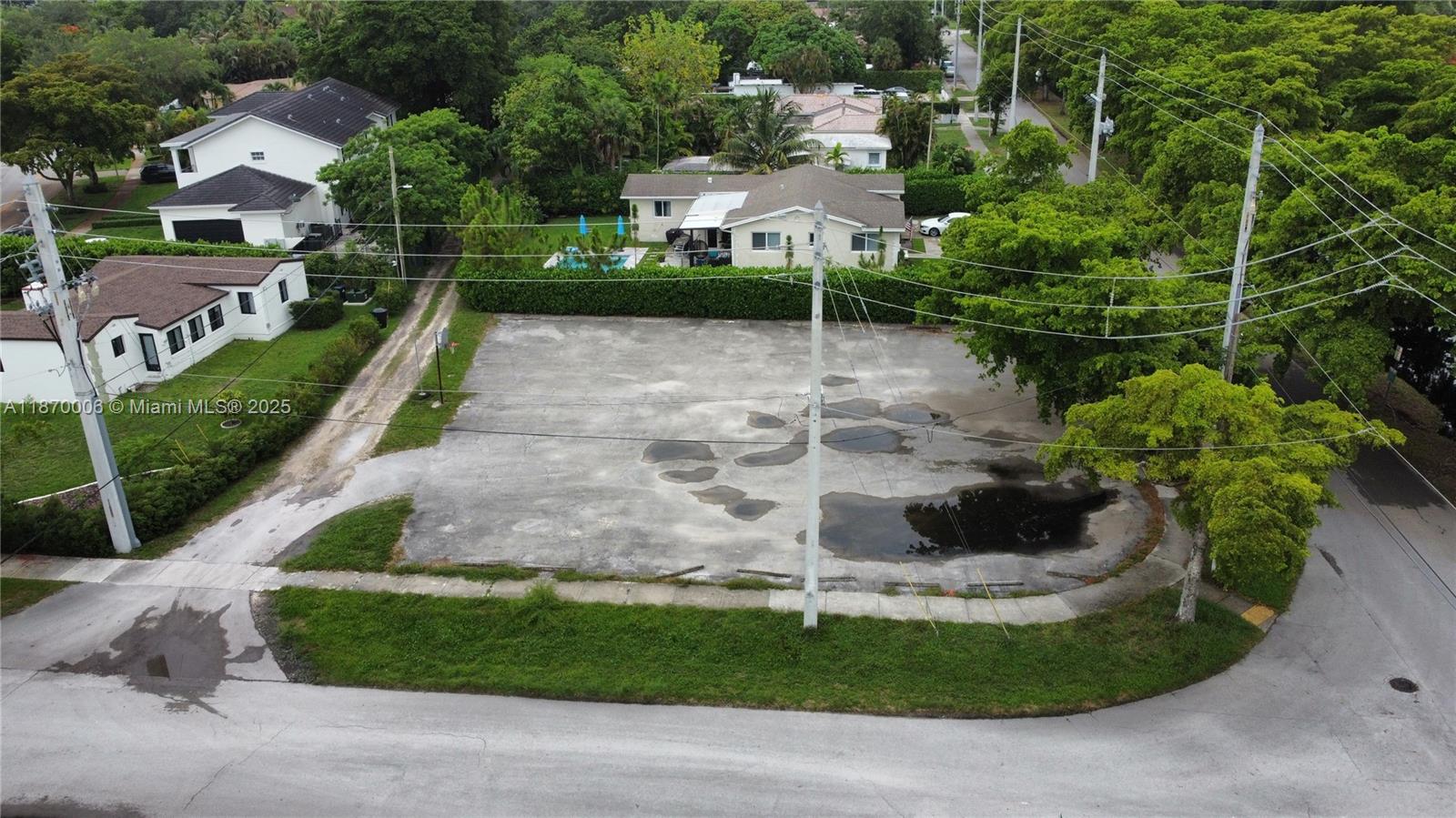 An aerial view shows a vacant paved lot surrounded by trees and residential houses — 425 Esplanade Dr, Miami Springs FL 33166, MIAMI SPRINGS, FL