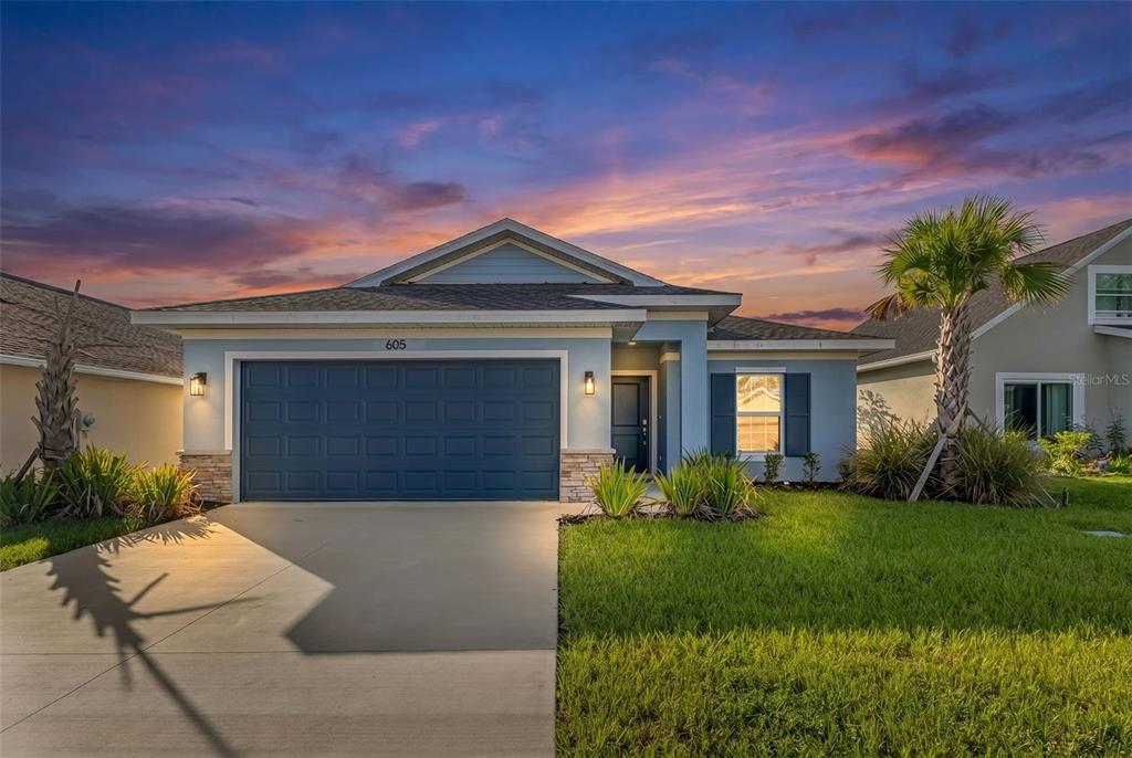A single-story blue house with a two-car garage and a palm tree in the yard — 605 ROSE APPLE CIRCLE, PORT CHARLOTTE, FL
