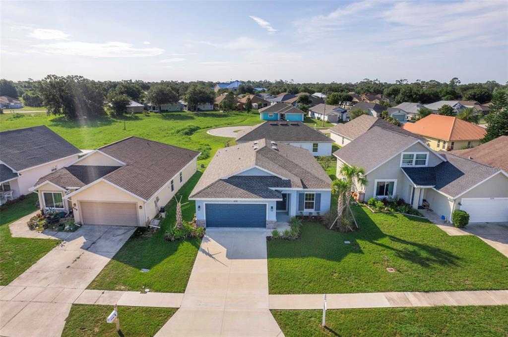 An aerial view shows a suburban street with several single-family homes and green lawns — 605 ROSE APPLE CIRCLE, PORT CHARLOTTE, FL