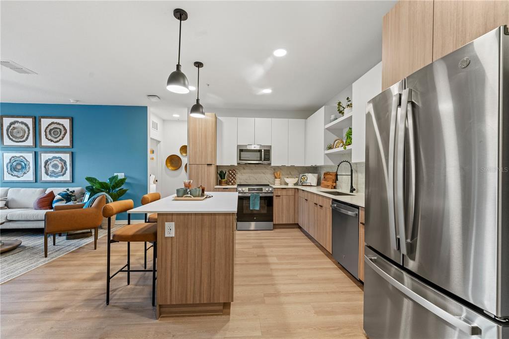 A modern kitchen with wood-tone cabinets, stainless steel appliances, and a central island — 2285 CROWN VILLAGE ROAD UNIT B3, OCOEE, FL