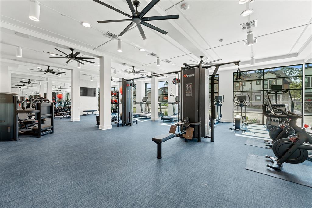 A bright fitness center features multiple exercise machines, ceiling fans, and large windows — 2285 CROWN VILLAGE ROAD UNIT B3, OCOEE, FL