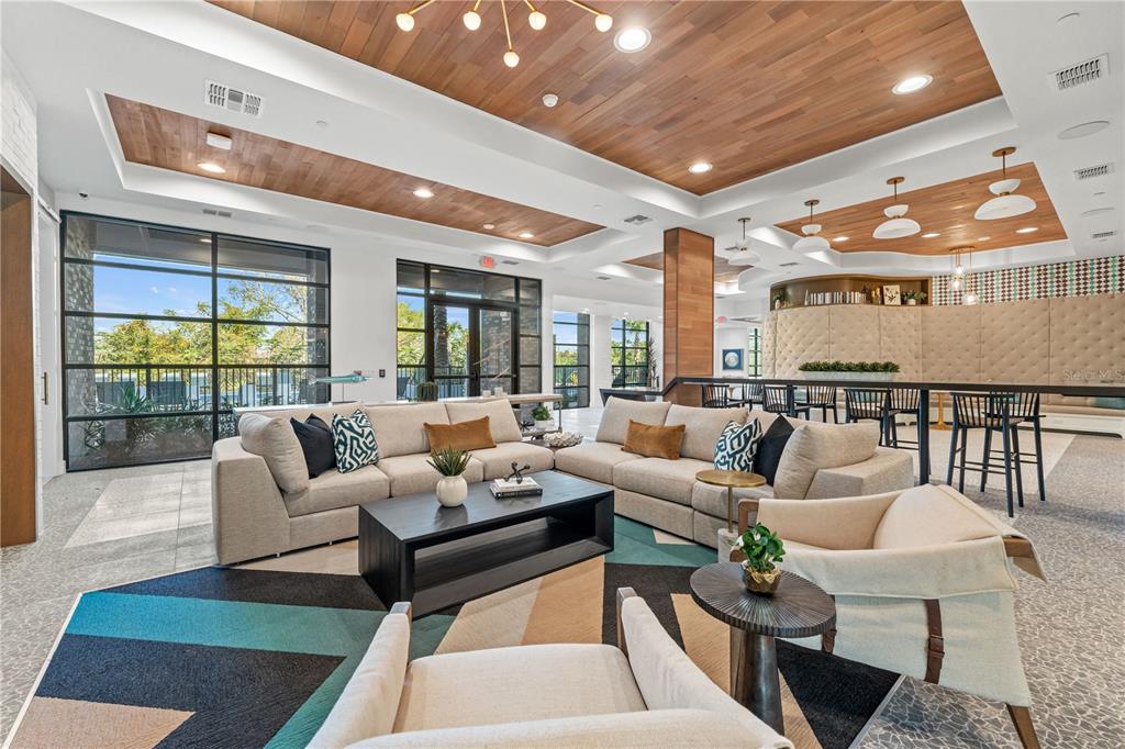 A modern lounge area features a wood-paneled ceiling, large windows, and contemporary furniture — 2285 CROWN VILLAGE ROAD UNIT B3, OCOEE, FL