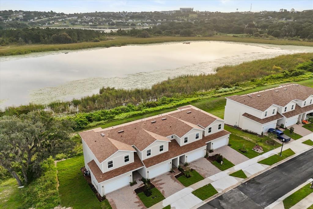 An aerial view shows two multi-unit townhouses situated next to a large lake — 925 LAKEFRONT VILLAGE DRIVE, CLERMONT, FL