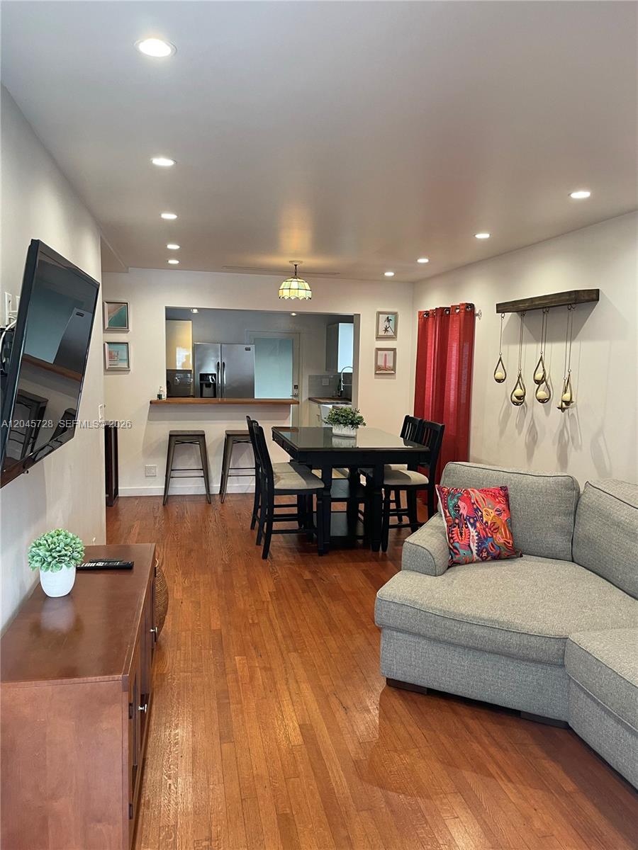 A living room with hardwood floors, a large gray sectional sofa, and an adjacent dining area — 2112 SW 60th Ct, Miami FL 33155, MIAMI, FL