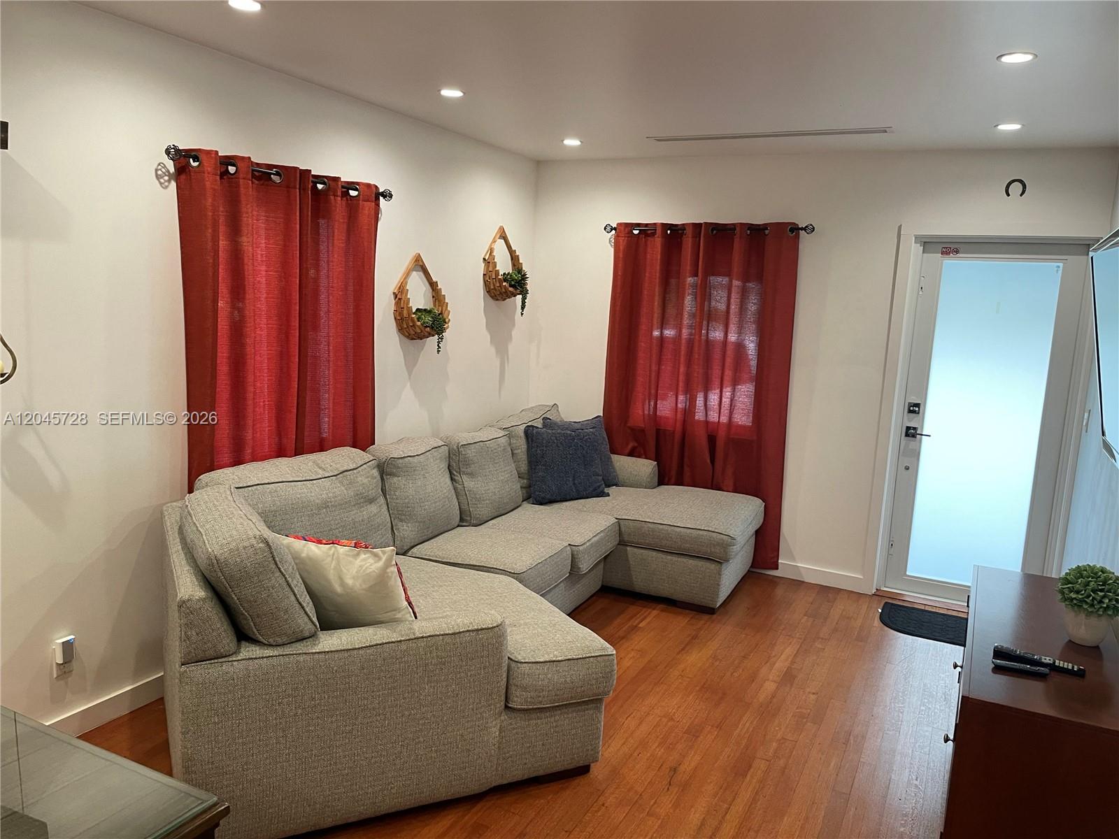 A living room features a gray sectional sofa, a wall-mounted television, and hardwood flooring — 2112 SW 60th Ct, Miami FL 33155, MIAMI, FL