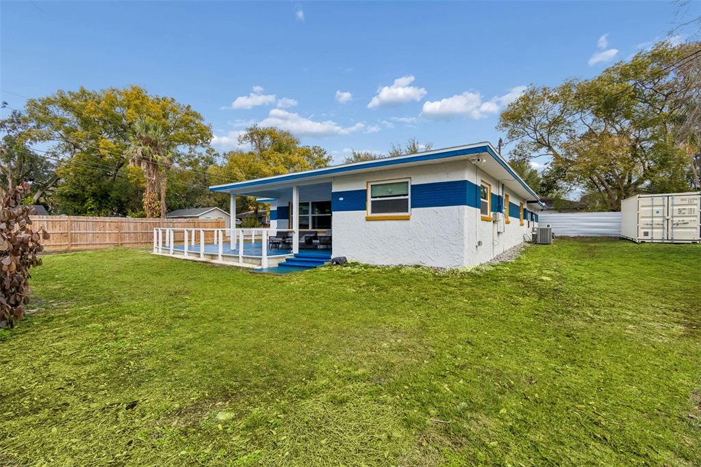 A white house with blue trim and a deck sits in a grassy backyard — 1102 E RIVER COVE STREET, TAMPA, FL