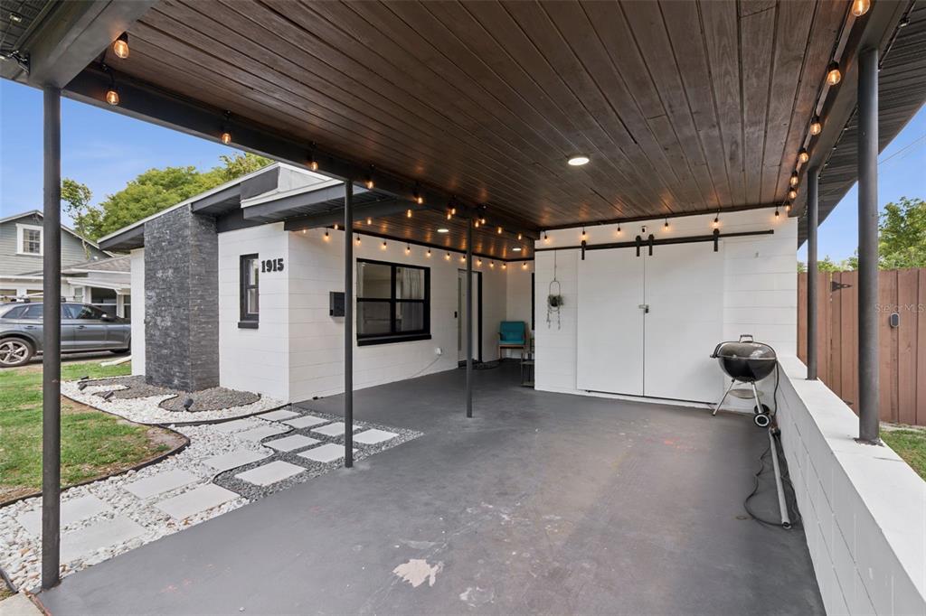 A covered carport features a dark wood ceiling, string lights, and a white storage closet — 1915 WEBER STREET, ORLANDO, FL