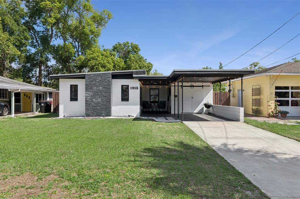 A single-story house with a white exterior, dark stone accent wall, and a covered carport — 1915 WEBER STREET, ORLANDO, FL