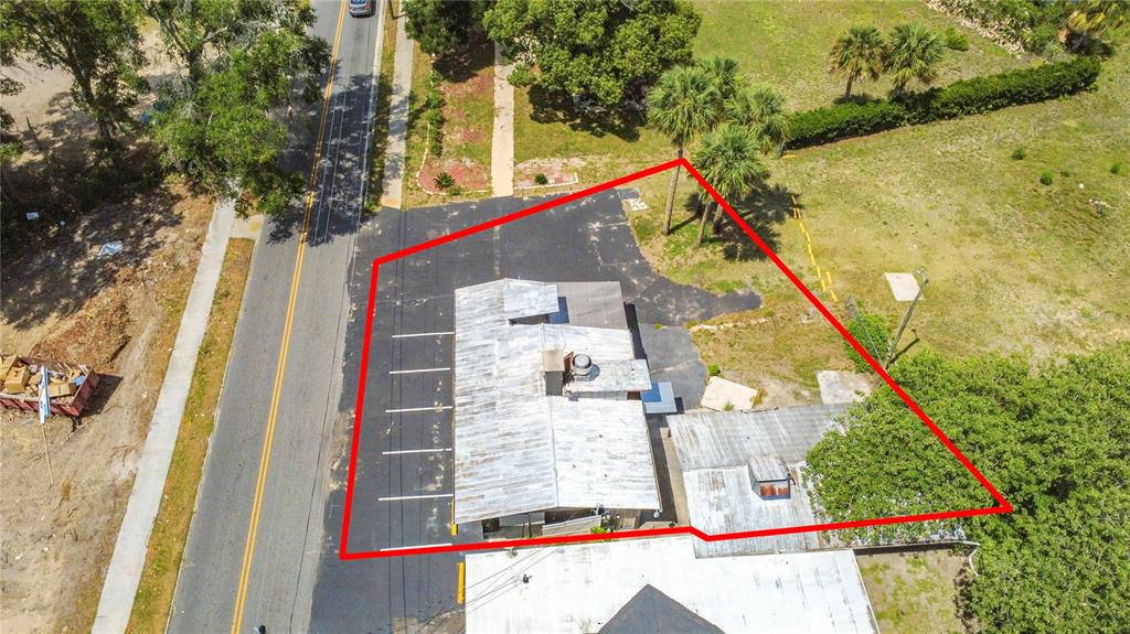 An aerial view shows a commercial building with a metal roof and adjacent parking lot — E BATES AVENUE, EUSTIS, FL