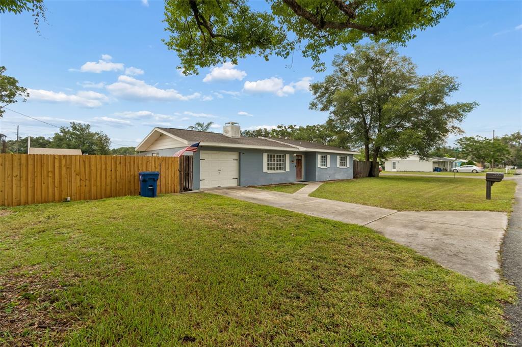 A single-story house with a gray exterior, a concrete driveway, and a wooden privacy fence — 39051 12TH AVENUE, ZEPHYRHILLS, FL