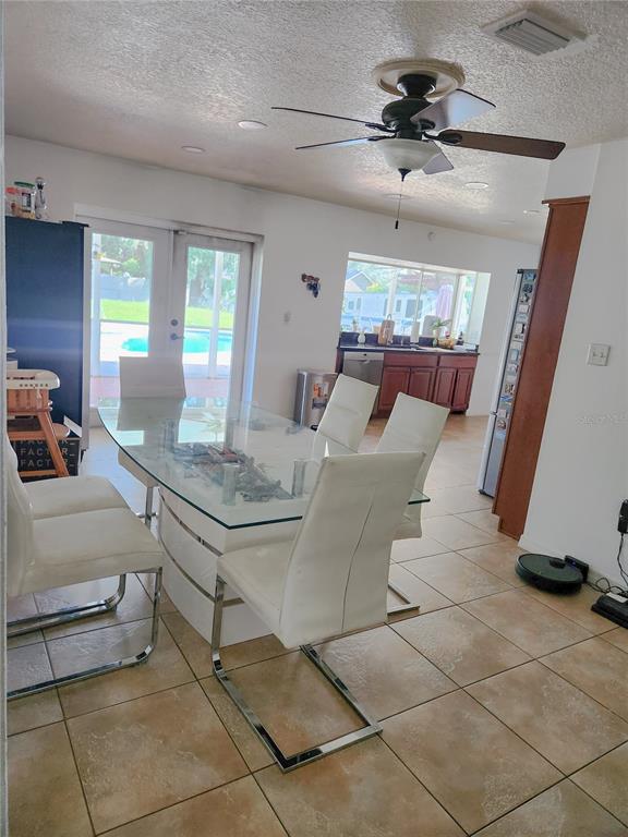 A dining area features a glass-topped table, white chairs, tile flooring, and a ceiling fan — 1682 STARFISH STREET, KISSIMMEE, FL