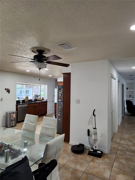 A dining area with a glass table leads into a kitchen with dark wood cabinets — 1682 STARFISH STREET, KISSIMMEE, FL