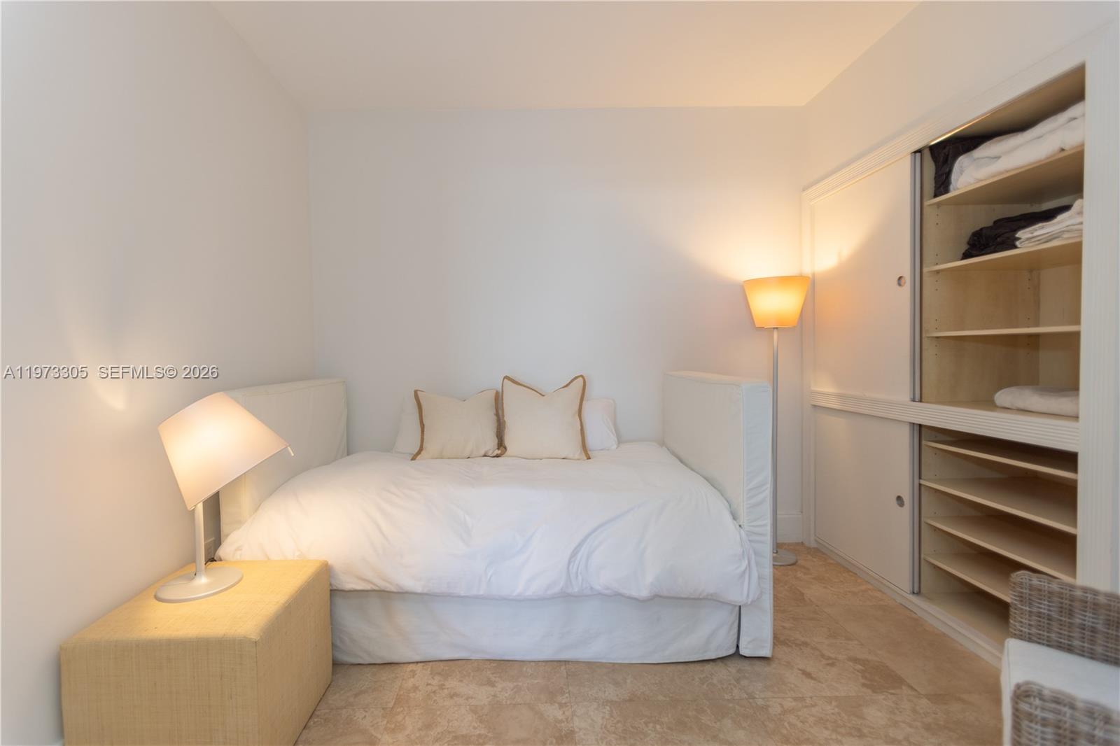 A bedroom features a daybed, a floor lamp, and an open closet with shelving — 9595 Collins Ave # F, Surfside FL 33154, SURFSIDE, FL