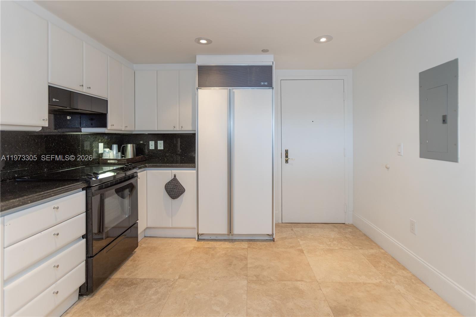 A kitchen features white cabinetry, black appliances, dark countertops, and light-colored floor tiles — 9595 Collins Ave # F, Surfside FL 33154, SURFSIDE, FL