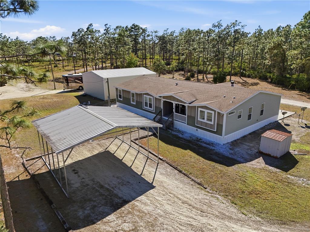 An aerial view shows a manufactured home with a carport, detached garage, and storage shed — 6844 CHAD JASON ROAD, ST CLOUD, FL