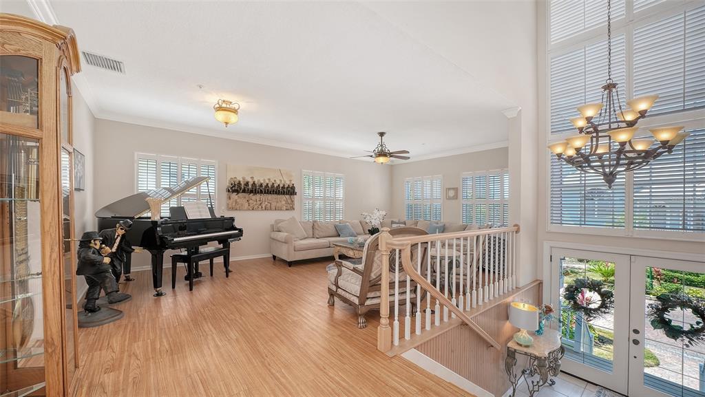 A living room features a grand piano, sectional sofa, wood flooring, and a large chandelier — 3040 GULF OF MEXICO DRIVE UNIT 3, LONGBOAT KEY, FL