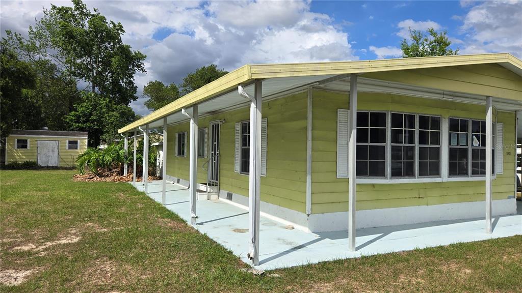 A light green mobile home with a covered porch and a detached shed in the yard — 5921 SW 63RD STREET, OCALA, FL