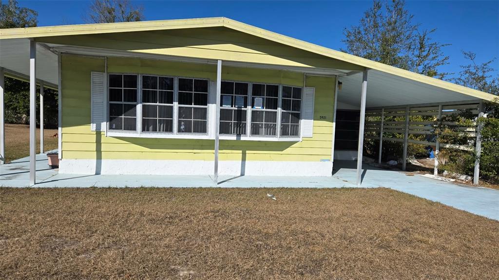 A yellow single-wide mobile home features a front carport, a covered porch, and large windows — 5921 SW 63RD STREET, OCALA, FL
