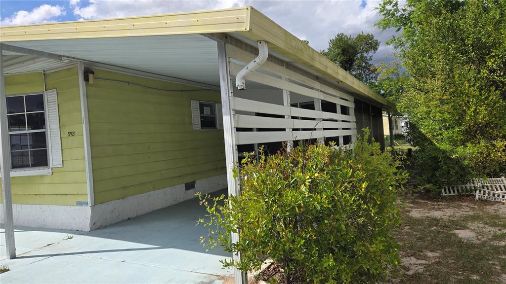 A light green mobile home features a covered carport with a white privacy screen — 5921 SW 63RD STREET, OCALA, FL
