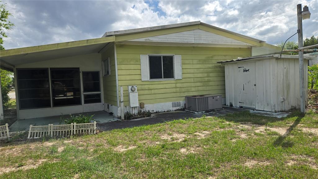 The exterior of a pale green mobile home features a screened porch and a shed — 5921 SW 63RD STREET, OCALA, FL