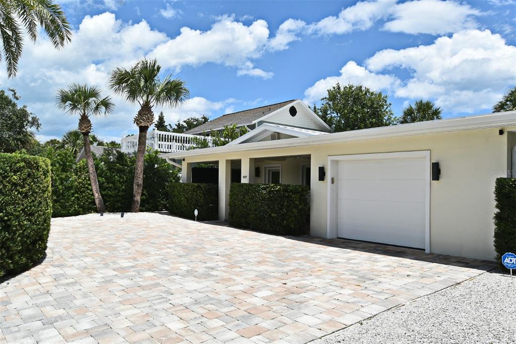 A paved driveway leads to a single-story house with a white garage and palm trees — 507 N PENINSULA AVENUE, NEW SMYRNA BEACH, FL