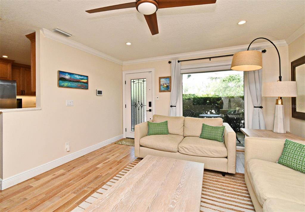 A living room features light wood floors, a beige sofa, and a large window — 507 N PENINSULA AVENUE, NEW SMYRNA BEACH, FL