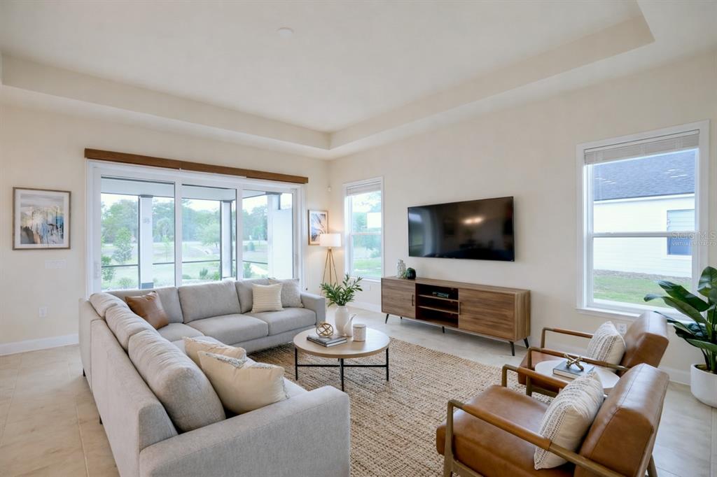 A living room features a sectional sofa, two leather chairs, a television, and large windows — 3612 SW 120TH TERRACE, GAINESVILLE, FL