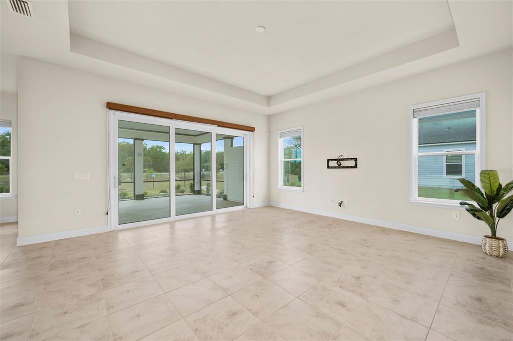A living room with tile floors, a tray ceiling, and sliding glass doors to a patio — 3612 SW 120TH TERRACE, GAINESVILLE, FL