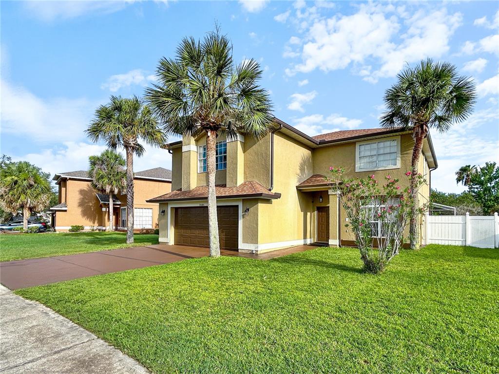 A two-story yellow stucco house with a two-car garage and palm trees in the yard — 1606 WOOD VIOLET DRIVE, ORLANDO, FL