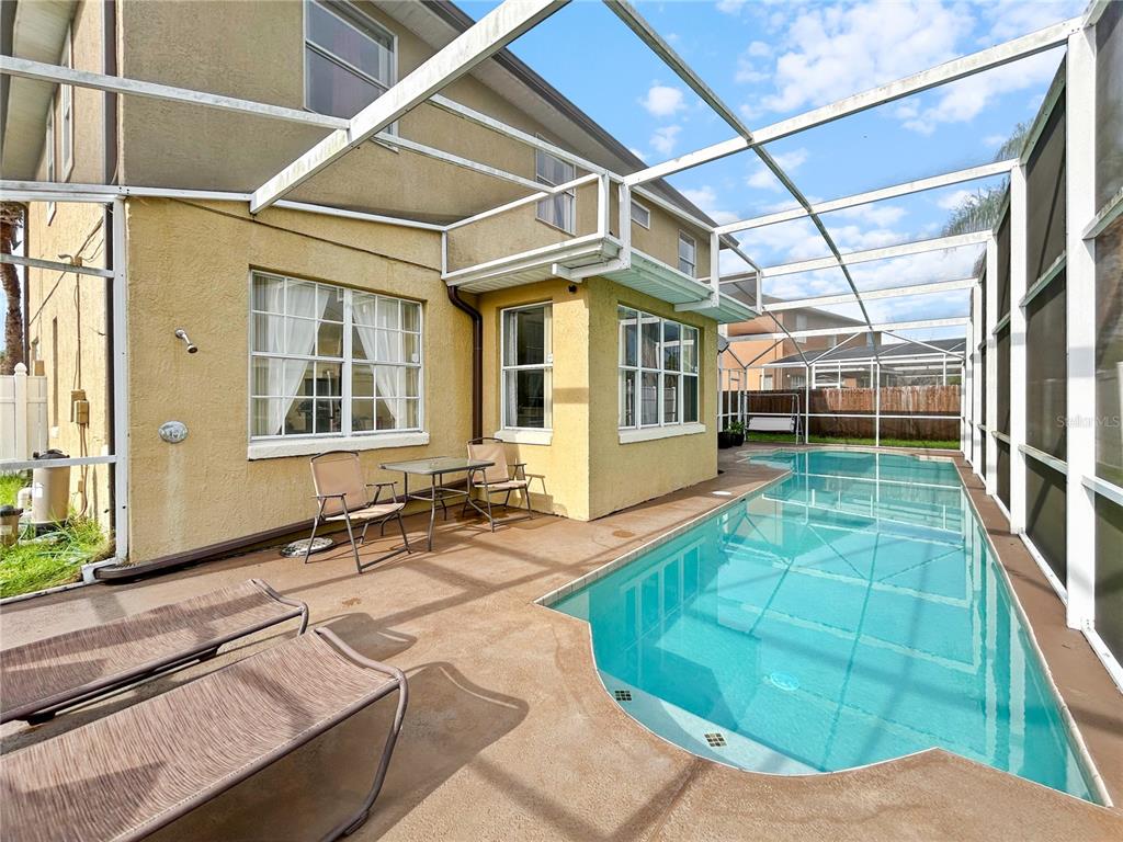 A swimming pool sits on a concrete patio enclosed by a screened-in lanai structure — 1606 WOOD VIOLET DRIVE, ORLANDO, FL
