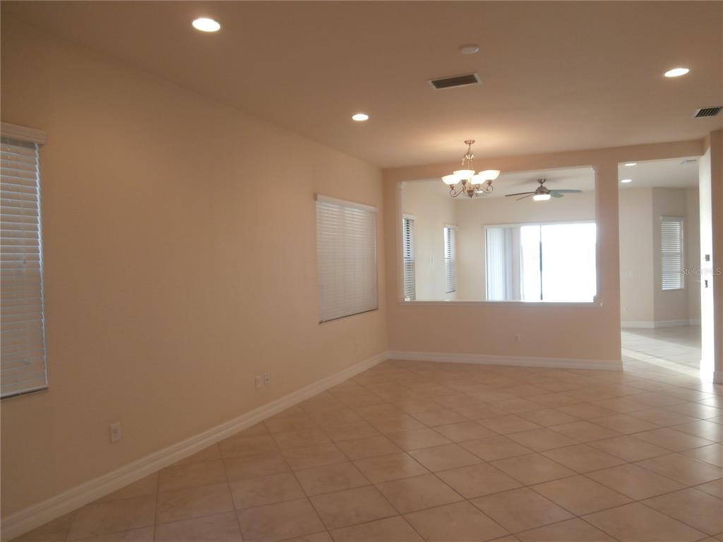 An open living area features beige walls, tile flooring, recessed lighting, and a chandelier — 13172 WOODFORD STREET, ORLANDO, FL