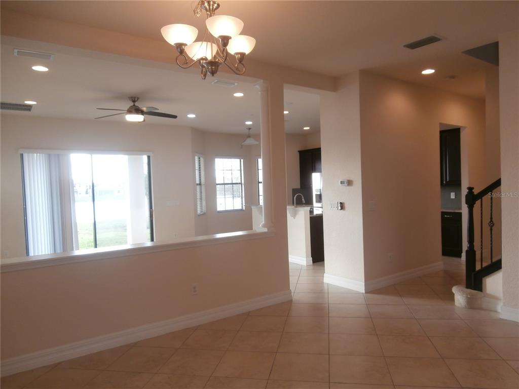 An interior view shows a tiled living area, a dining space with a chandelier, and stairs — 13172 WOODFORD STREET, ORLANDO, FL
