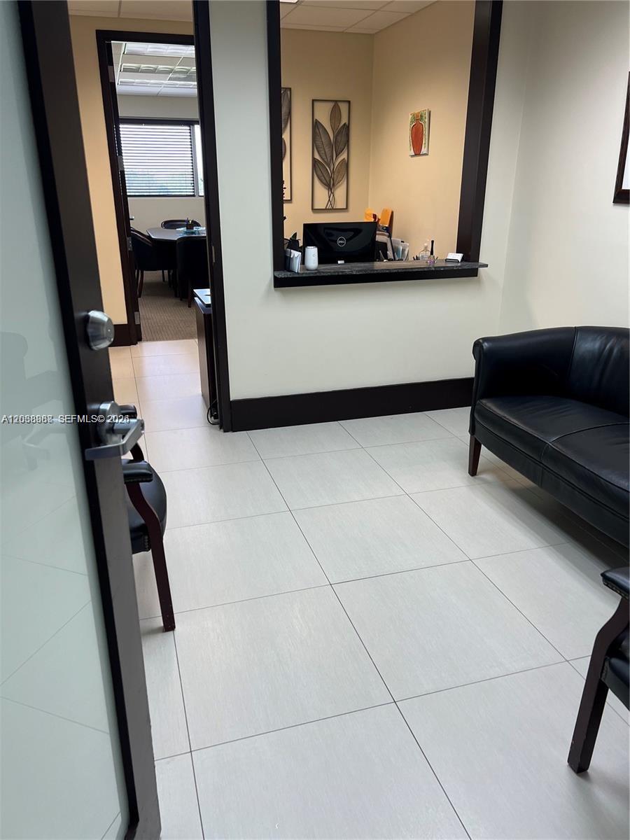 A waiting area with a black leather sofa leads to an office with a service window — 7480 SW 40th St # 750, Miami FL 33155, MIAMI, FL